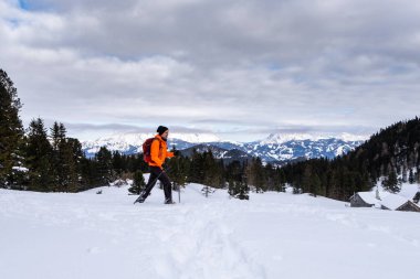 Kışın Scheibelalm holiday Resort Hohentauern panoramik manzaralı Ennstaler Alps için dağlar Reichenstein, Hochtor ve Grosser Oedstein üzerinde turuncu ceket snowshoeing adam