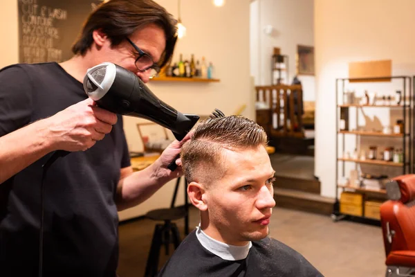 Erkek Kuaför Saç Kurutma Makinesiyle Genç Bir Adamın Saçını Kurutuyor Telifsiz Stok Imajlar