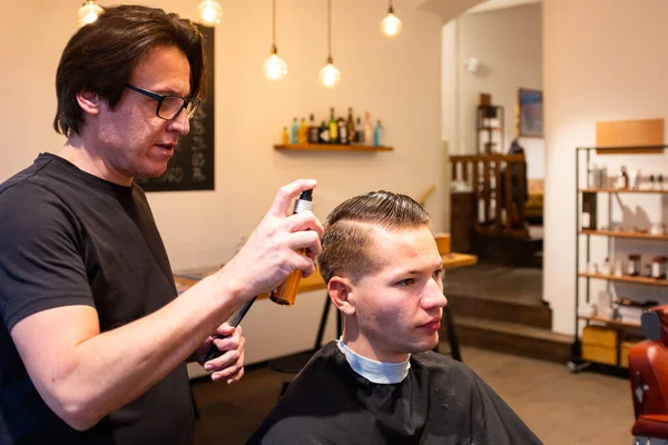 Barbeiro Umedece Cabelo Jovem Com Uma Garrafa Spray Sua Barbearia Fotografia De Stock