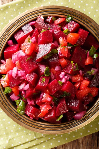 African food: Moroccan beetroot salad with onions, tomatoes and herbs close-up on the table. Vertical top view from abov