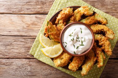 Masaya bir tabak sos ve limon yakın çekim ile breading içinde derin yağda kızartılmış altın avokado kısmı. Abov üzerinden yatay üstten görünüm