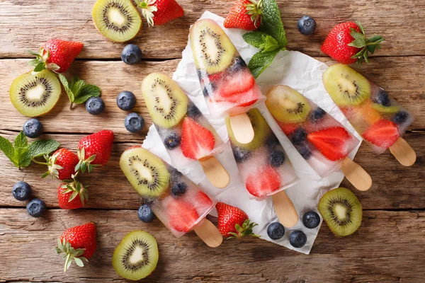 新鲜准备的冰棒冰与新鲜的草莓 猕猴桃和蓝莓在一张桌子上的棍子特写 Abov 的水平顶部视图 — 图库照片
