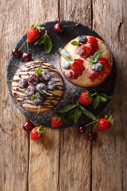 Hassas kek Çikolata, nane ve çilek, kiraz ve yaban mersini yakın çekim tablosundaki ile. Abov gelen dikey üstten görünüm