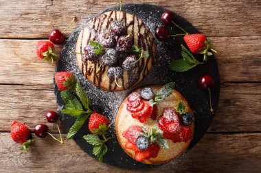 Bisküvi kek dekore çikolata, toz şeker, nane ve yaz meyveleri yakın çekim kayrak bir gemide. abov üzerinden yatay üstten görünüm