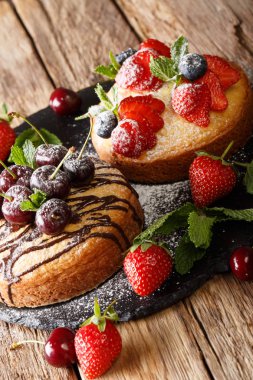 Çikolata ile iki kek fırından yeni çıkmış, nane, çilek, kiraz ve yaban mersini yakın çekim masanın üzerinde. Vertica