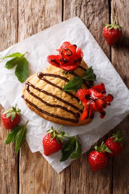 Lezzetli pandispanya kalp şeklinde çikolata ve çilek gül yakın çekim masada dekore. Abov gelen dikey üstten görünüm
