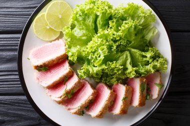 Panko marul ve limon portre siyah bir tabloda bir tabakta ile lezzetli biftek ahi tuna ekmek kırıntıları. abov üzerinden yatay üstten görünüm
