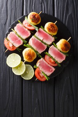 Barbekü taze ton balığı, domates, patates ve masanın üzerine şişleri yakın çekim yeşil soğan. Abov gelen dikey üstten görünüm