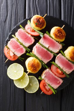 Lezzetli Kebap şişleri taze ton balığı, domates, patates ve masada yeşil soğan yakın çekim üzerinde. Abov gelen dikey üstten görünüm