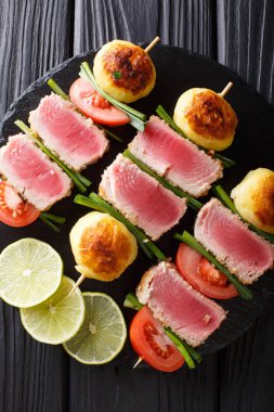 Ton balığı, domates, patates ve yeşil soğan yakın çekim bir tablo üzerinde kebap. Abov gelen dikey üstten görünüm