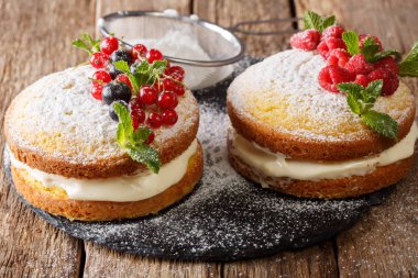 Lezzetli sandviç Victoria kek siyah ve kırmızı kuş üzümü, ahududu ve nane closeup masanın üzerinde. Horizonta