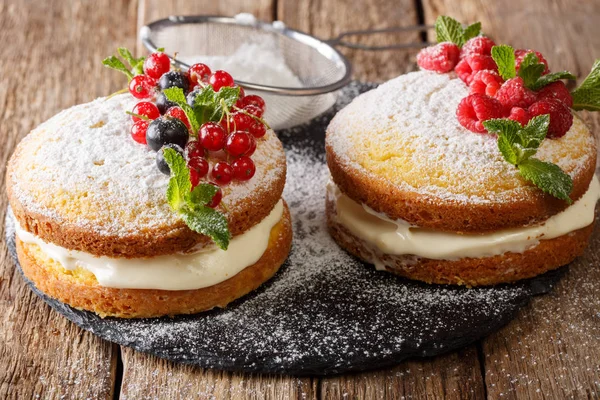 Lezzetli sandviç Victoria kek siyah ve kırmızı kuş üzümü, ahududu ve nane closeup masanın üzerinde. Horizonta