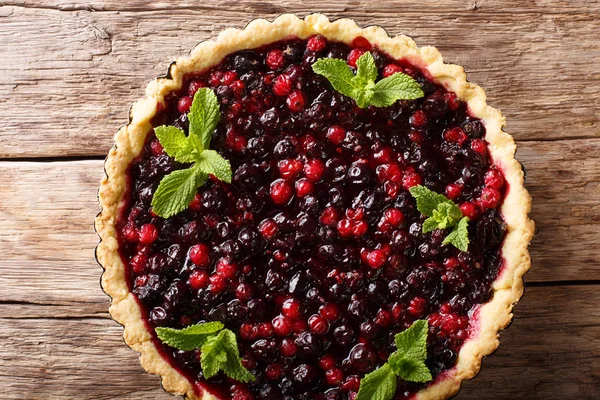 Frenk üzümü çilek, yaban mersini ve kızılcık yakın çekim bir pişirme çanağı bir tablo içinde ile rustik sulu tart. Abov üzerinden yatay üstten görünüm