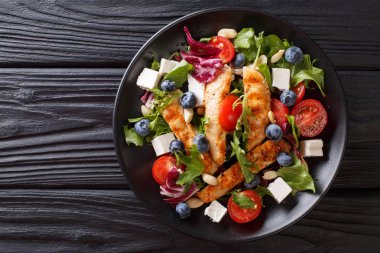 Izgara tavuk salata, yaban mersini, beyaz peynir, fındık, domates ve karışım marul yakın çekim bir plaka üzerine yaz. abov üzerinden yatay üstten görünüm