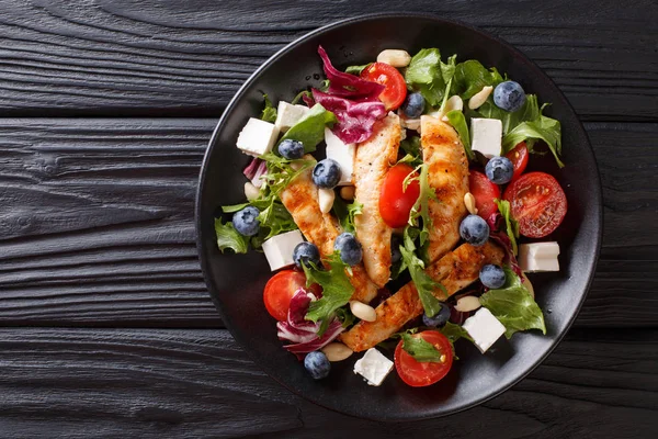 Izgara tavuk salata, yaban mersini, beyaz peynir, fındık, domates ve karışım marul yakın çekim bir plaka üzerine yaz. abov üzerinden yatay üstten görünüm