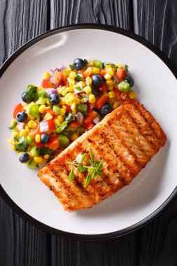 Plaka masada biber, Mısır, yaban mersini ve soğan salata closeup ile somon ızgara biftek. Abov gelen dikey üstten görünüm