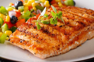 Mısır, yaban mersini ve biber makro bir plaka üzerinde salsa ile ızgara somon fileto. Horizonta