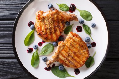 Bir tabloda bir plaka üzerinde hassas yaban mersini sosu ve ıspanak closeup ile lezzetli ızgara domuz biftek. abov üzerinden yatay üstten görünüm