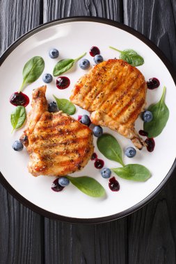 Bir tabloda bir plaka üzerinde hassas yaban mersini sosu ve ıspanak closeup ile lezzetli ızgara domuz biftek. Abov gelen dikey üstten görünüm