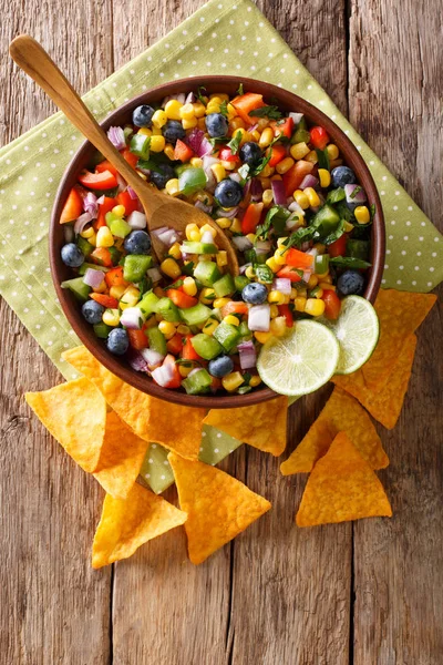 Mısır, yaban mersini, jalapeno biber, biber ve soğan lezzetli salata cips cips yakın çekim tablo ile servis edilir. Abov gelen dikey üstten görünüm