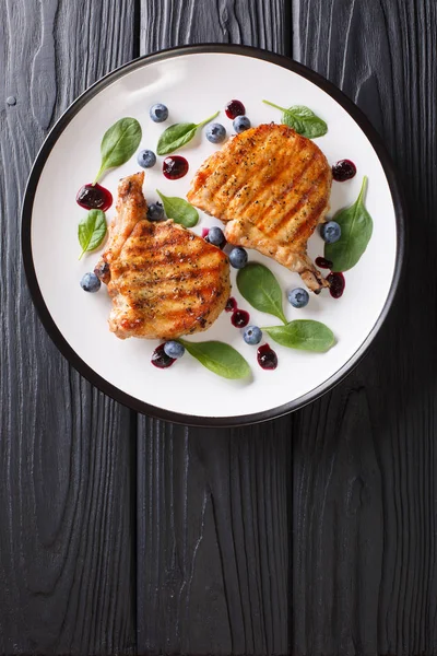 Yaban mersini sosu ve ıspanak yakın çekim bir plaka üzerinde ızgara domuz biftek. Abov gelen dikey üstten görünüm