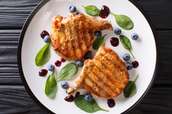 Bir tabloda bir plaka üzerinde hassas yaban mersini sosu ve ıspanak closeup ile lezzetli ızgara domuz biftek. abov üzerinden yatay üstten görünüm