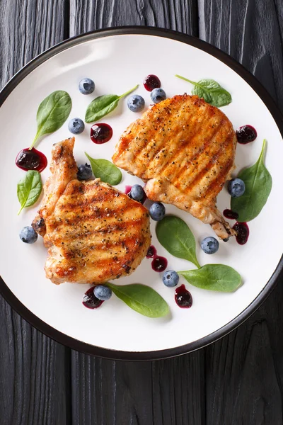 Bir tabloda bir plaka üzerinde hassas yaban mersini sosu ve ıspanak closeup ile lezzetli ızgara domuz biftek. Abov gelen dikey üstten görünüm