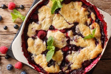 bir tabloda bir pişirme çanağı içinde ahududu ve yaban mersini yakın çekim sıcak tatlı tart. Abov üzerinden yatay üstten görünüm