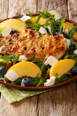 Organik ızgara tavuk salatası, Taze şeftali, yaban mersini, roka ve beyaz peynir yakın çekim bir tabloda bir tabakta. Vertica