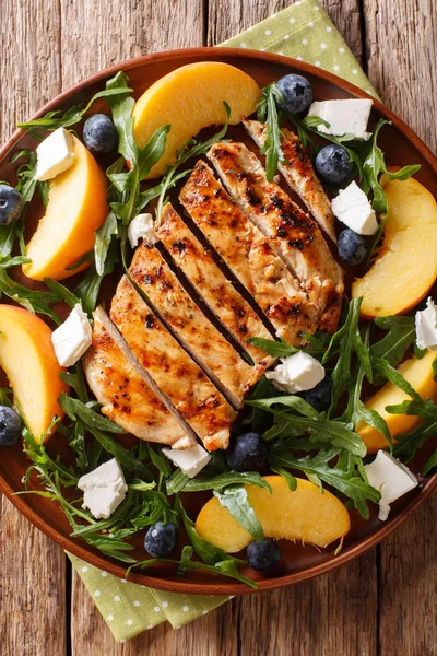 Izgara tavuk, şeftali, yaban mersini, bir tablo bir tabağa roka ve peynir yakın çekim yaz salatası. Abov gelen dikey üstten görünüm