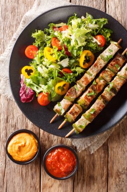Tablo plaka ve sosu bir yakın çekim üzerinde taze sebze salatası ile lezzetli Kebap şişleri üzerinde. Abov gelen dikey üstten görünüm