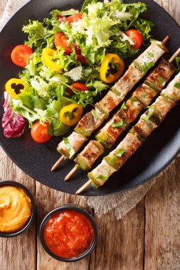 Bir tablo bir plaka ve soslar yakın çekim üzerinde sebze taze salata ile domuz eti şiş kebap. Abov gelen dikey üstten görünüm