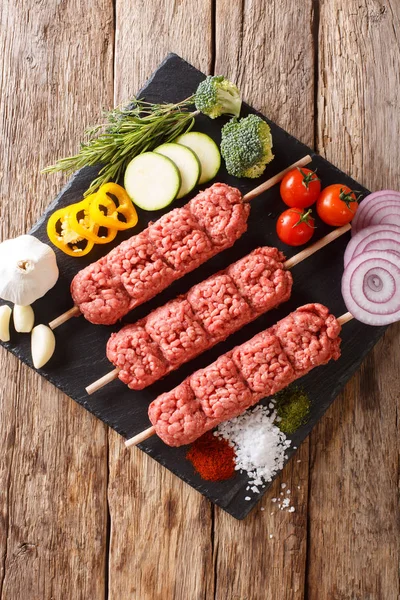 生カフタ ひき肉の串にテーブルの上の食材や野菜のクローズ アップから Kofte ケバブ Abov から垂直のトップ ビュー — ストック写真