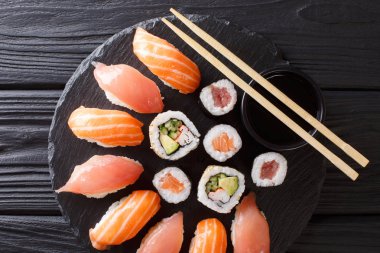 Suşi bir dizi somon ve ton balığı ile servis, California, maki, soya sosu portre siyah arduvaz tahtası masanın üzerine alır. Abov üzerinden yatay üstten görünüm