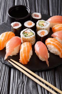 Japon menü. Suşi somon ve ton balığı ile lezzetli kümesi, California rulo, maki, soya sosu portre siyah arduvaz tahtası masanın üzerinde. Vertica