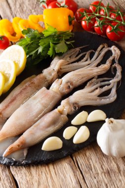 Deniz ürünleri taze mürekkep balığı dokunaçları yakın çekim ve masada yemek pişirmek için sebze ile. Vertica