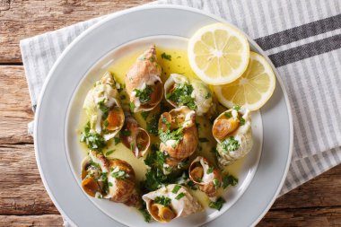 Fransız kabuklu deniz ürünleri bulot whelks tereyağı, sarımsak ve maydanoz, limon yakın çekim masada bir sos ile servis. Abov üzerinden yatay üstten görünüm