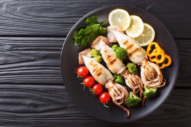 Izgara kalamar tentacles ile domates, brokoli, bir tabloda bir tabakta limon ve biber closeup ile. Abov üzerinden yatay üstten görünüm