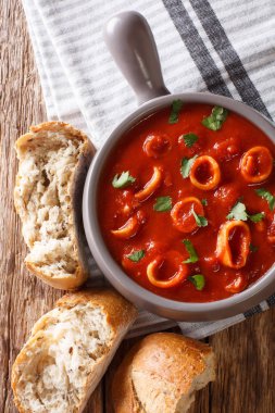 Domates baharat ve maydanoz yakın çekim bir pot ve taze ekmek ile geleneksel Akdeniz deniz ürünleri kalamar halkaları. abov gelen dikey üstten görünüm