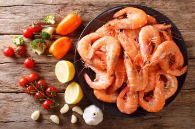 boiled tiger shrimps on a plate and fresh vegetables close-up on a table. Horizontal  top view from abov clipart