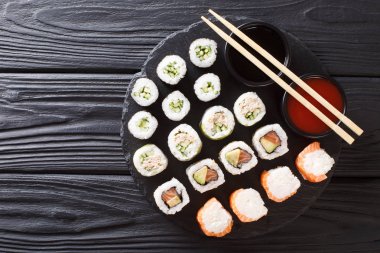 Set Japonca ürün yelpazesine maki, uramaki rulo, hosomaki yakın çekim bir taş tahta üzerinde servis edilir. abov üzerinden yatay üstten görünüm