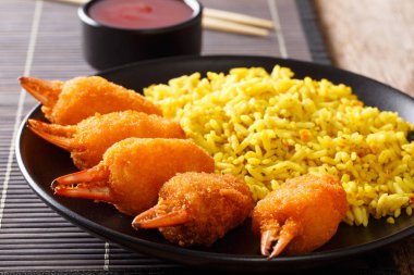 Kızarmış ekmek kırıntıları ile baharatlı sarı pirinç yakın çekim bir plaka üzerinde bir tablo içinde yengeç pençeleri. Horizonta