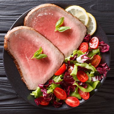 Taze sebze salatası yakın çekim siyah bir arka plan ile ızgara sığır eti biftek dilimlenmiş. abov üzerinden üstten görünüm