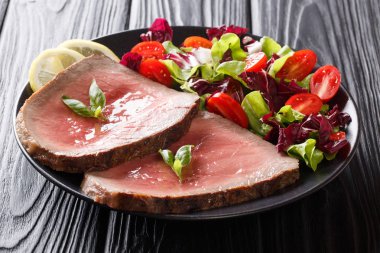 Orta sığır eti biftek siyah bir tabloda bir tabakta sebze salatası yakın çekim ile kavrulmuş. Horizonta