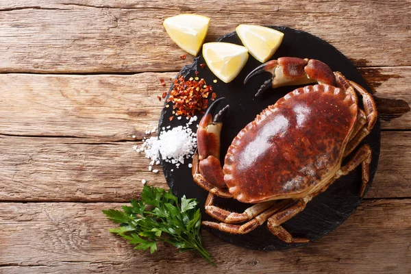 Raw brown crab with lemon, parsley and spices on a slate board c