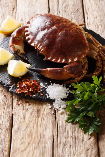 Country style: raw edible brown crab with ingredients for cooking close-up on a wooden table. vertica