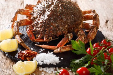 Lüks ham Örümcek Yengeci taze domates, limon, otlar ve baharatlar yakın çekim siyah bir taş çevrili. Horizonta