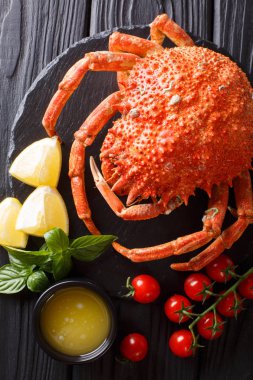 Lezzetli yemekler: örümcek yengeç domates, limon ve bir kara tahta üzerinde eritilmiş tereyağı yakın çekim ile haşlanmış. Abov gelen dikey üstten görünüm