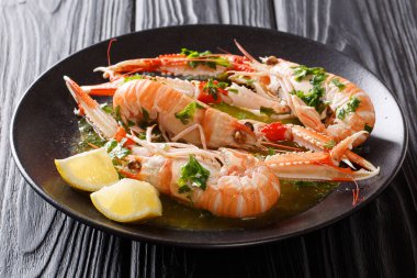 Taze pişmiş kerevitleri, limonlu karides ve otlar yakın siyah bir tabloda bir plaka üzerinde çekim ile lezzetli sos. Horizonta