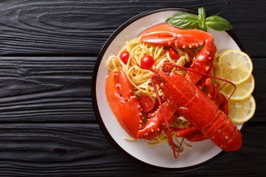 Pahalı spagetti ve pişmiş ıstakoz, domates, limon ve taze otlar yakın çekim bir tabakta servis edilmektedir. Üstten yatay üstten görünüm. Kopya girintili